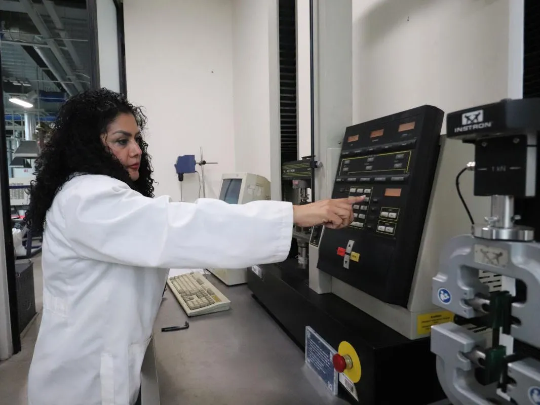 Profesora del centro operando una máquina universal de ensayos en el laboratorio de materiales